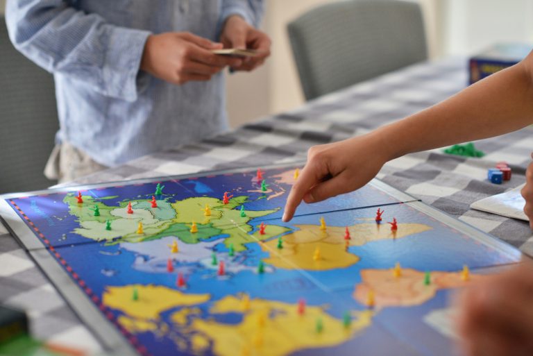 Person pointing to map on Risk board game